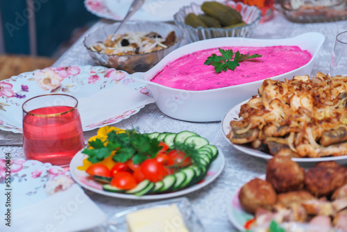 Festive table with food for New Year or Christmas. Pickled cucumbers and mushrooms, fried fish with onions, Shuba salad, chopped vegetables, fried cutlets, compote.