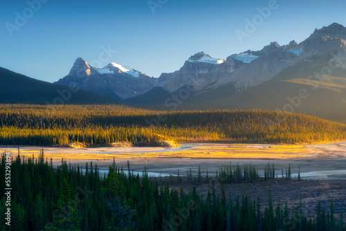 Mountain landscape at dawn. Sunbeams in a valley. Rivers and forest in a moun...