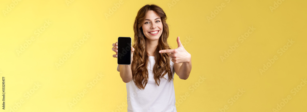 Upbeat confident good-looking female showing photo smartphone display hold mobile phone extended arm camera pointing index finger cellphone screen smiling delighted promote app internet application - obrazy, fototapety, plakaty 