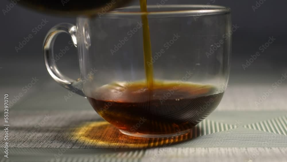The video shows how hot tea is poured into a glass cup standing on the table. The video shows how hot tea is poured into a glass cup standing on the table.