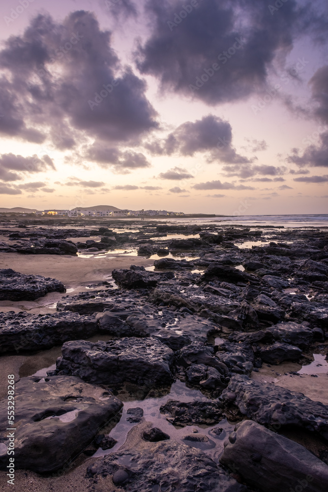 Obraz premium Sunset over the coastline of Famara beach on the Atlantic Ocean in Lanzarote, Canary Islands, Spain