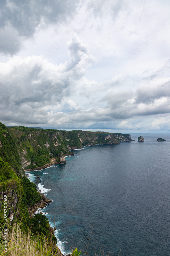 Beautiful coastline view from Saren Cliff Point. Clear water and rocks with cloudy sky. Nusa Penida, Indonesia.