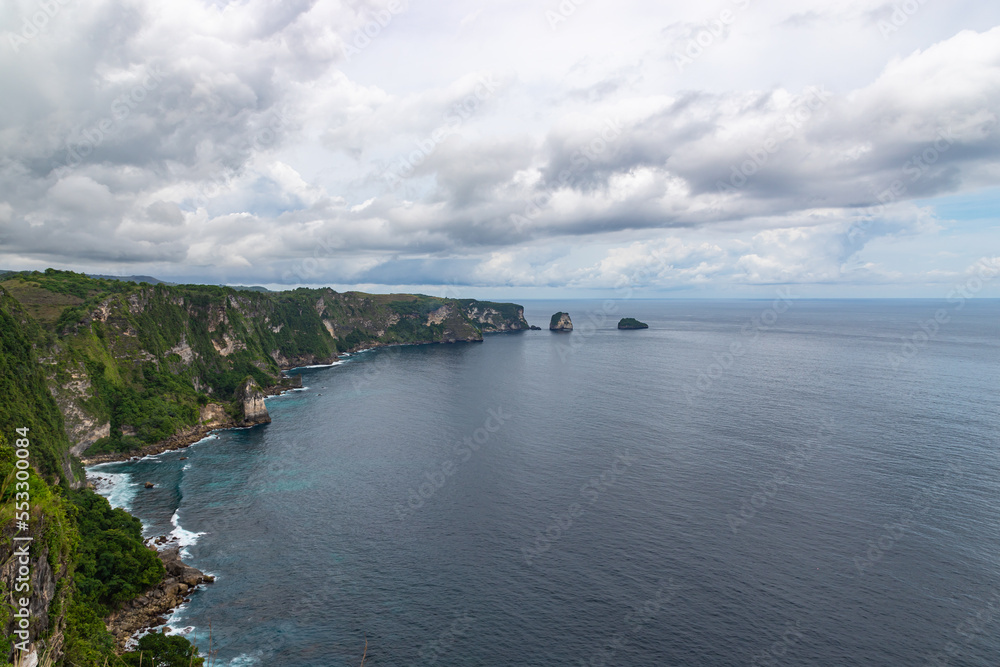 Beautiful coastline view from Saren Cliff Point. Clear water and rocks with cloudy sky. Nusa Penida, Indonesia.