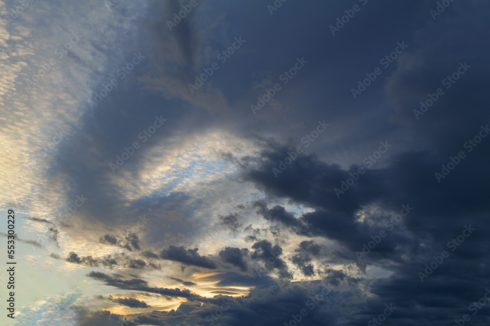 Fototapeta premium Summer evening sky in the picturesque clouds, lit by the rays of the setting sun.