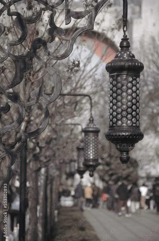 Vintage street lamps on the walking path of the public garden in Istanbul Hagia Sophia with silhouette of nomadic people . Street photography