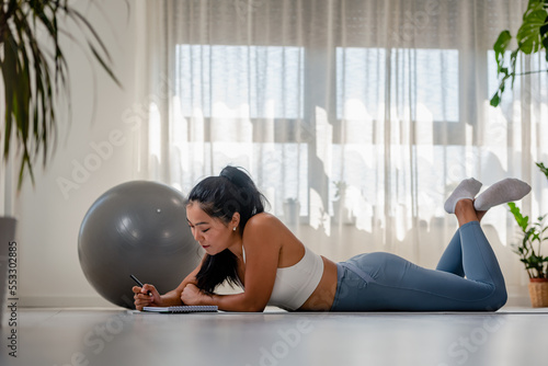 Schilderij op canvas Young Asian yoga woman writing in her notebook