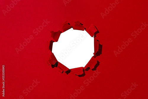 Small hole in red paper, empty space for advertising text in torn paper, background texture photo