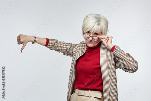 beautiful elderly woman with glasses gives a thumbs down. the concept of a business woman leader