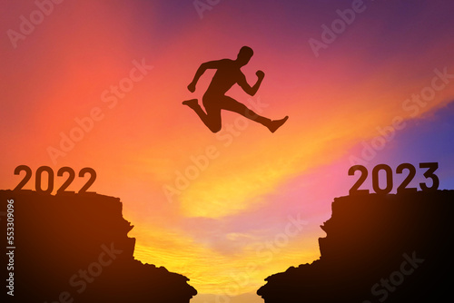 man jump from 2022 to 2023 at sunset  - new year 2023 concept