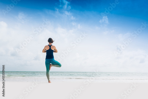 Caucasian woman practicing yoga at seashore