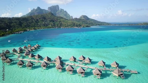4K Aerial Drone footage of water villa bungalows and Mount Otemanu in Bora Bora, Tahiti, French Polynesia. Turquoise blue lagoon in Bora Bora. Luxury, romantic vacation, honeymoon exotic destination.