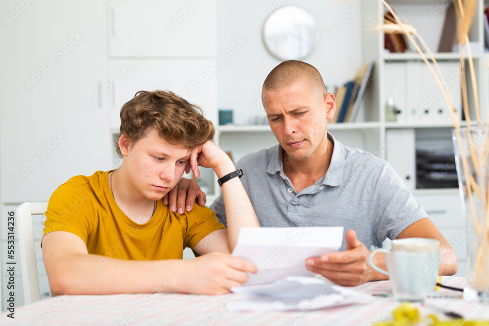 Son and dad feeling upset because they're reading letter that contains bad tidings.