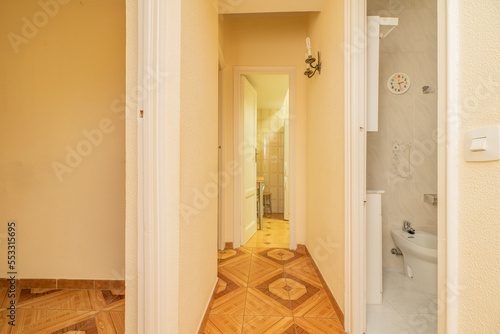 Distributor corridor of a vintage house with orange floors and access to the kitchen and toilet