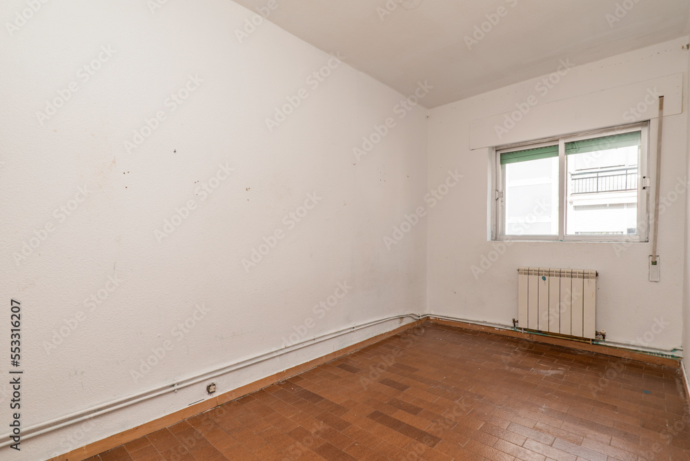 Fototapeta premium Empty living room with ugly brown tile floors, exposed heating pipes and white aluminum radiators