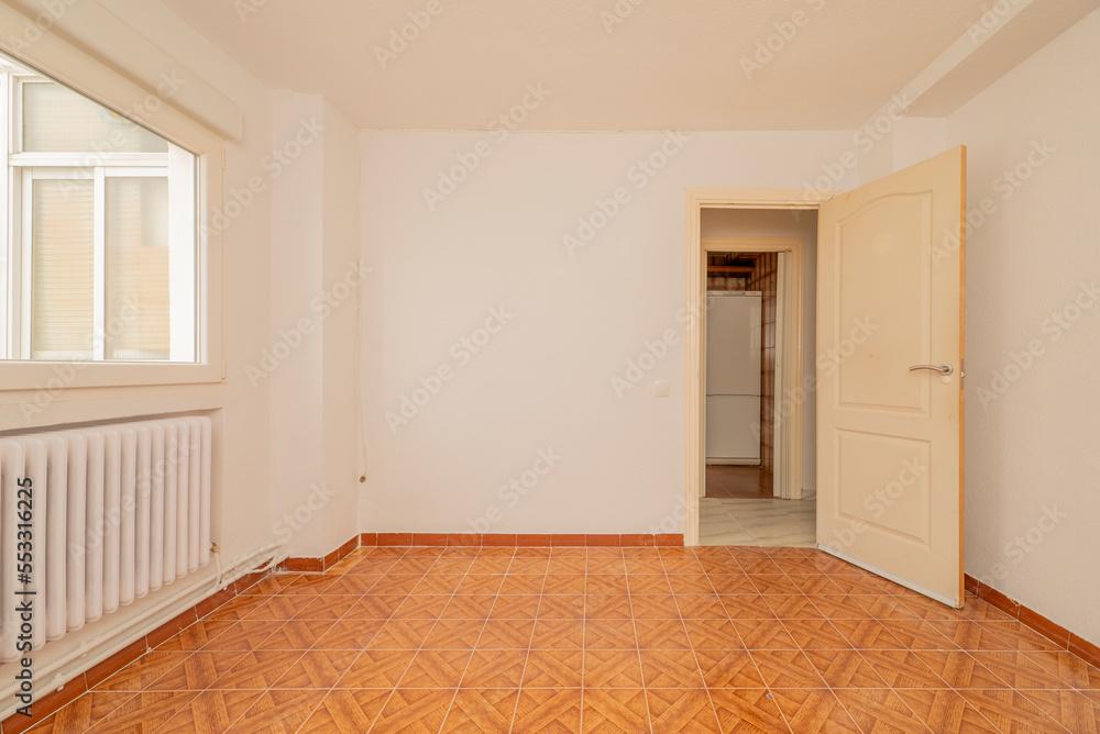 Fototapeta premium Empty living room with ugly brown tiled floor, orange painted walls, electric heater and white ceiling fan