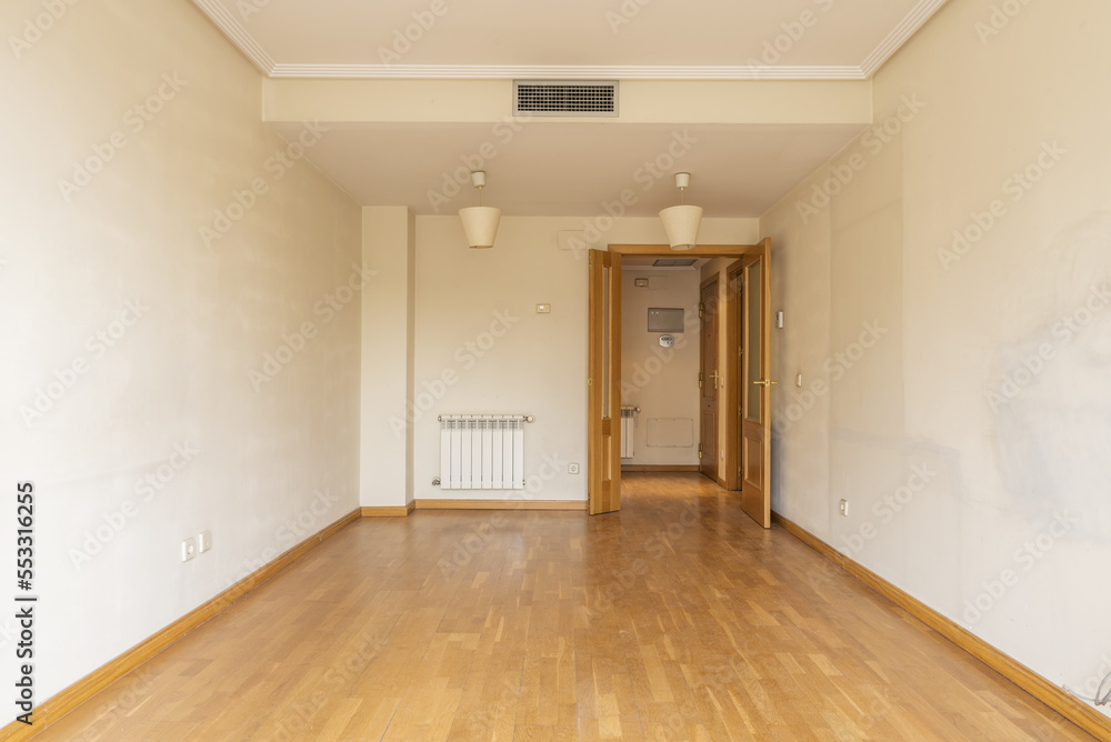 An empty room with double wooden doors, an aluminum radiator, air conditioning through hidden ducts in the false ceiling and oak parquet floors. An empty room with double wooden doors, an aluminum radiator, air conditioning through hidden ducts in the false ceiling and oak parquet floors.