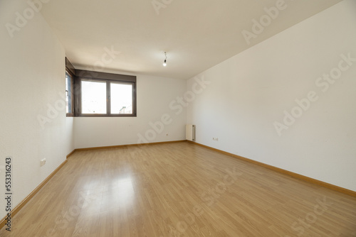 empty living room with wooden flooring and brown anodized aluminum corner windows