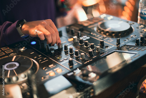 DJ plays live set and mixing music on turntable console on stage at nightclub. Disc Jockey Hands on a sound mixer station at club party. SELECTİVE FOCUS