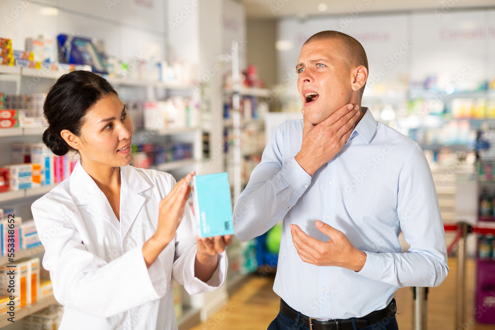 Man complains to a female pharmacist about a sore throat. Help in choosing a medicine in a pharmacy