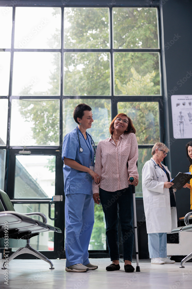 Medical assistant giving support to injured patient trying to walk with ...