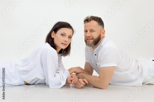 Portrait of sporty family lying after training on white background. Middle-aged man holding hands of young woman. Sport.