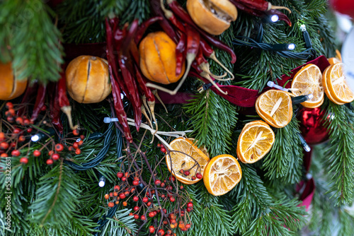 Fir branches decorated with dried tangerines, oranges, garlands and red berries for Christmas