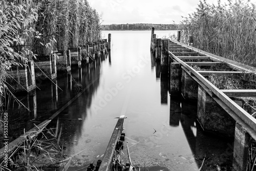 Old pier on the lake. Autumn landscape. Black and white.