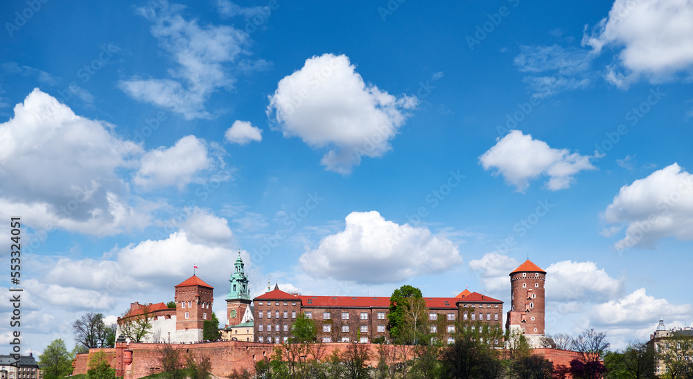 Riverside of Krakow City in Poland with Wawel castle view. Shot taken from across river Vistula. Summer day, blue sky with clouds.