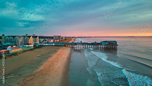 Aerial view over beach in Maine during sunrise with town and old wood pier of shops