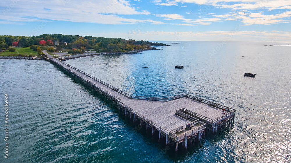 Aerial over large walking pier for tourists attached to Maine coast