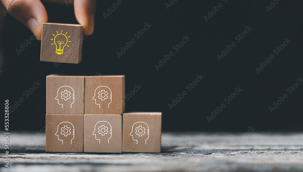 Concept creative idea and innovation. Hand choose wooden cube block with head human symbol and light bulb icon. knowledge and education concept. learning with smart technology. Concept creative idea and innovation. Hand choose wooden cube block with head human symbol and light bulb icon. knowledge and education concept. learning with smart technology.