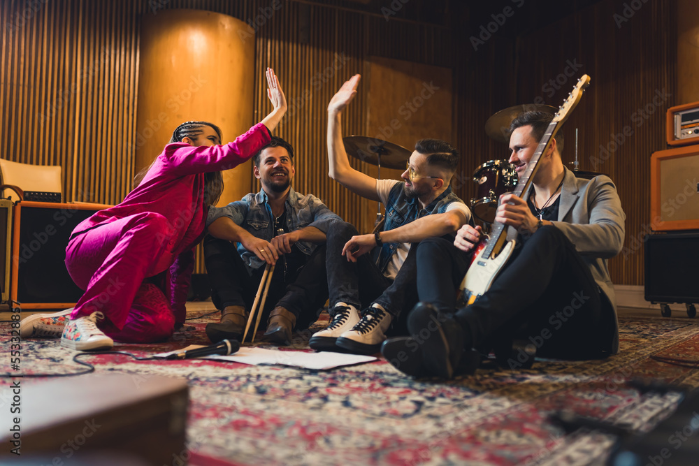music band members sitting on the floor and celebrating their great idea, music concept. High quality photo