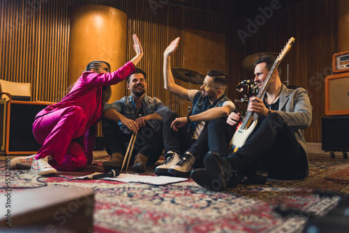 music band members sitting on the floor and celebrating their great idea, music concept. High quality photo
