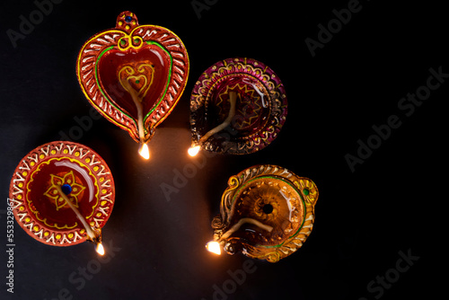 Happy Diwali. Colorful clay diya lamps lit during Diwali celebration on black background. Diwali celebration of Hindus.