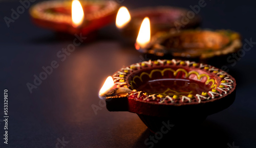 Happy Diwali, Diya lamps lit during Diwali celebration on black background.