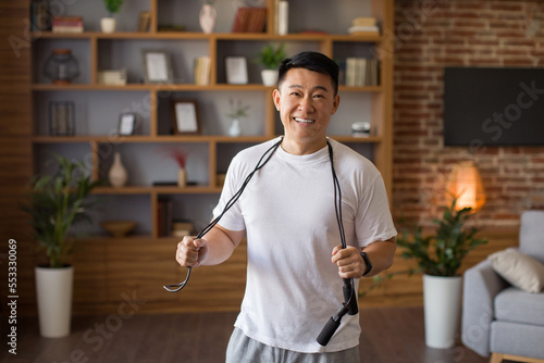 Photography Excited asian middle aged man standing with skipping rope hang around his neck,