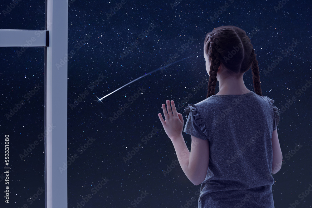Little girl near window looking at shooting star in beautiful night sky ...