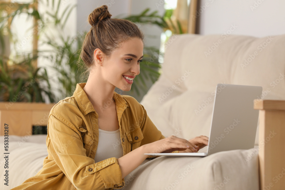 Happy young woman with laptop in living room Happy young woman with laptop in living room