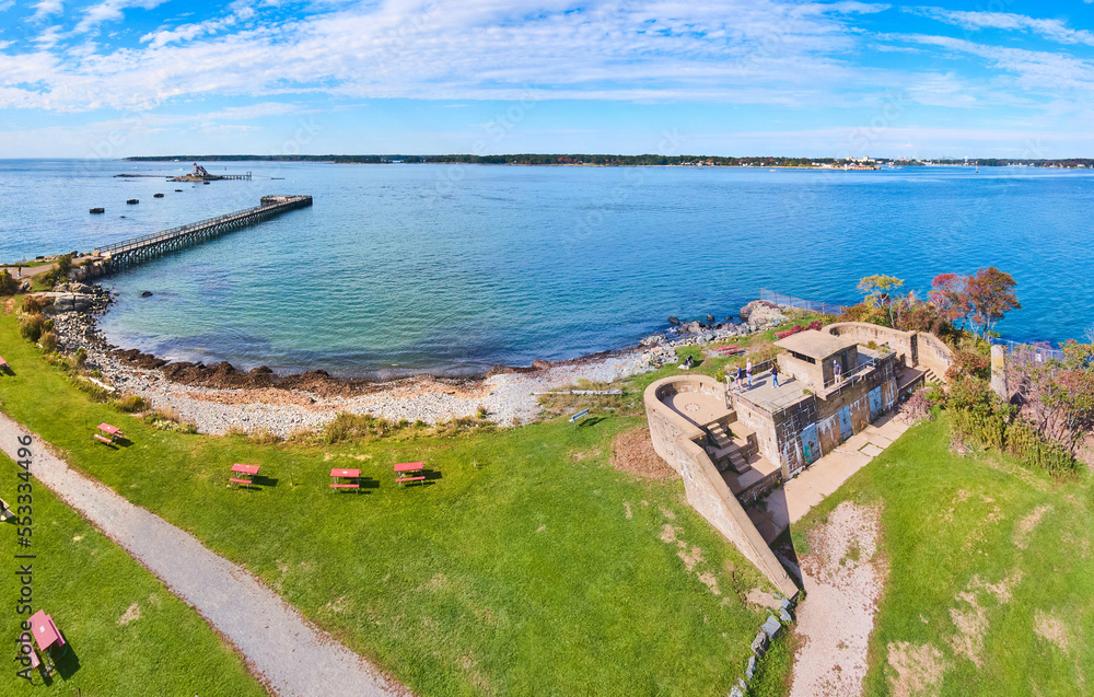 Old military fort on coast of Maine with pier and small island lighthouse in distance
