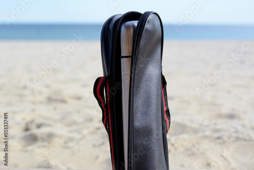 Metallic thermos in black stylish case on sandy beach