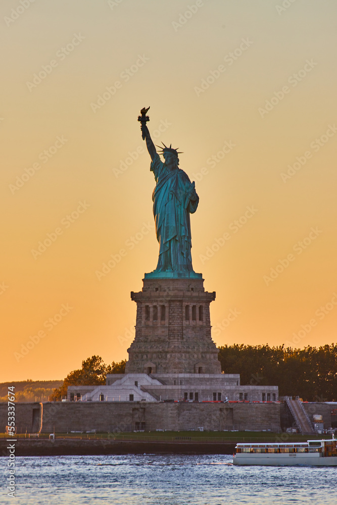 New York City golden hour light around iconic Statue of Liberty in dusk