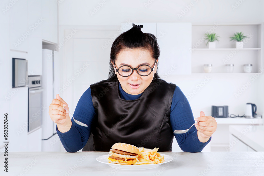 Happy fat woman eating junk foods in kitchen Happy fat woman eating junk foods in kitchen