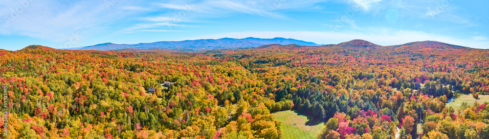 Panoramic aerial over peak fall forest mountains in Vermont with blue skies