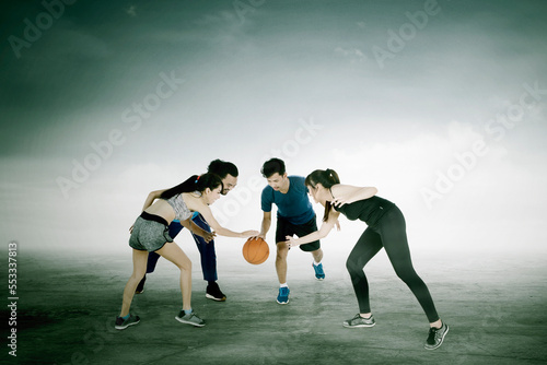 Group of people bouncing a basketball while training