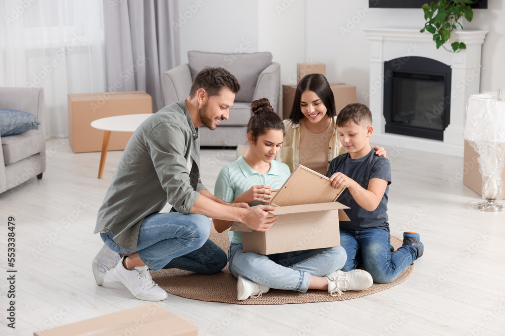 Happy family settling into new house and unpacking boxes on floor. Moving day Happy family settling into new house and unpacking boxes on floor. Moving day