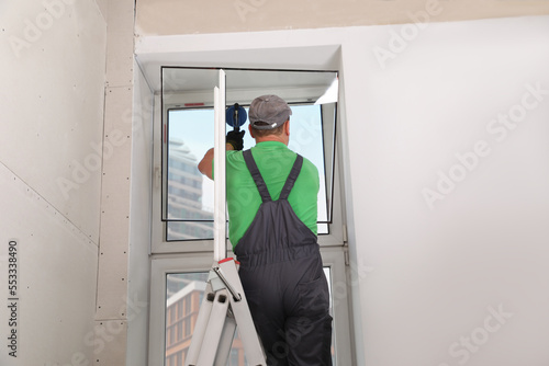 Canvas-taulu Worker using suction lifter for double glazing window installation indoors, back