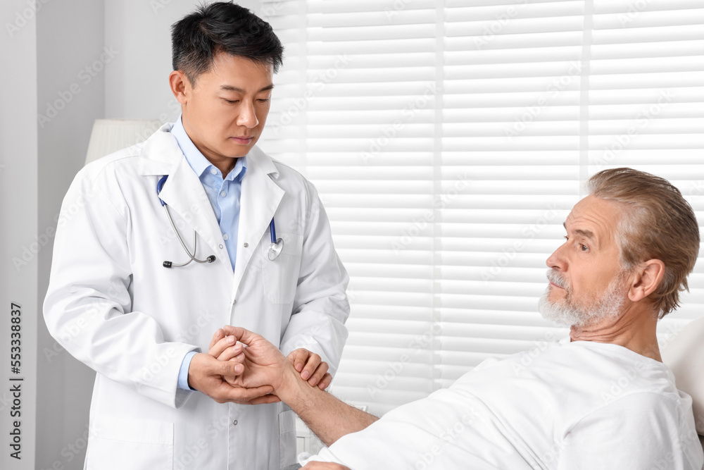 Doctor checking senior man`s pulse in hospital Doctor checking senior man`s pulse in hospital