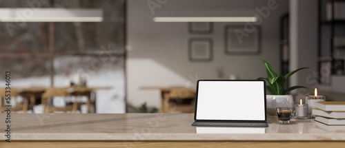 Tabletop with tablet mockup and copy space against blurred background of co-working space