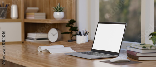 Laptop mockup is on the wooden table with decor against the window. minimalist workspace. © bongkarn