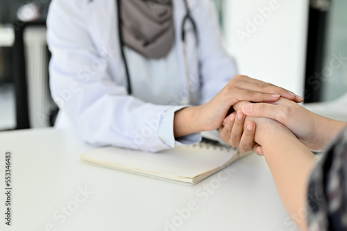 Close-up image, A doctor reassuring a patient by gently holding the patient hands
